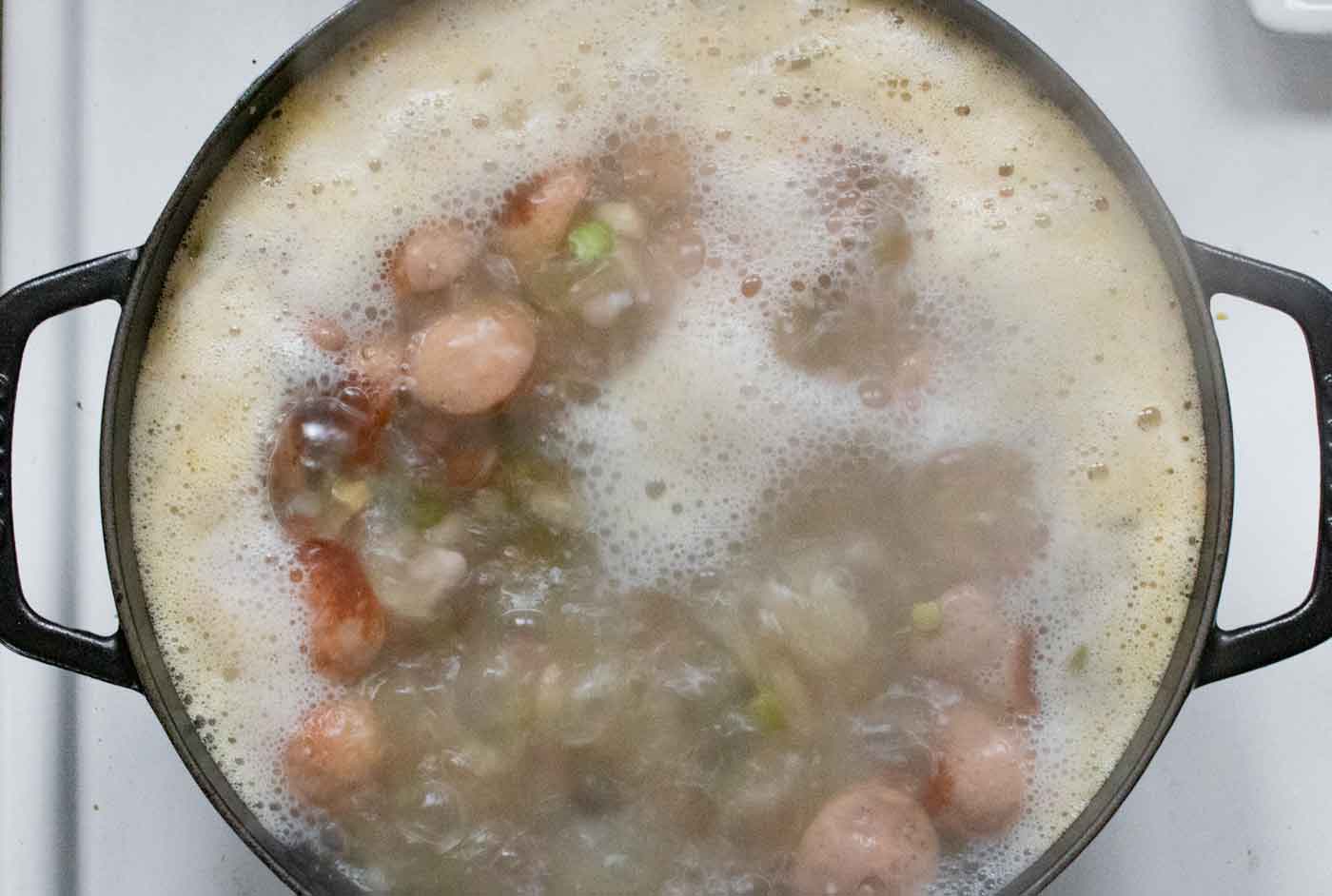 Overhead view of the soup pot with bubbling soup, and foam that needs to be skimmed off.