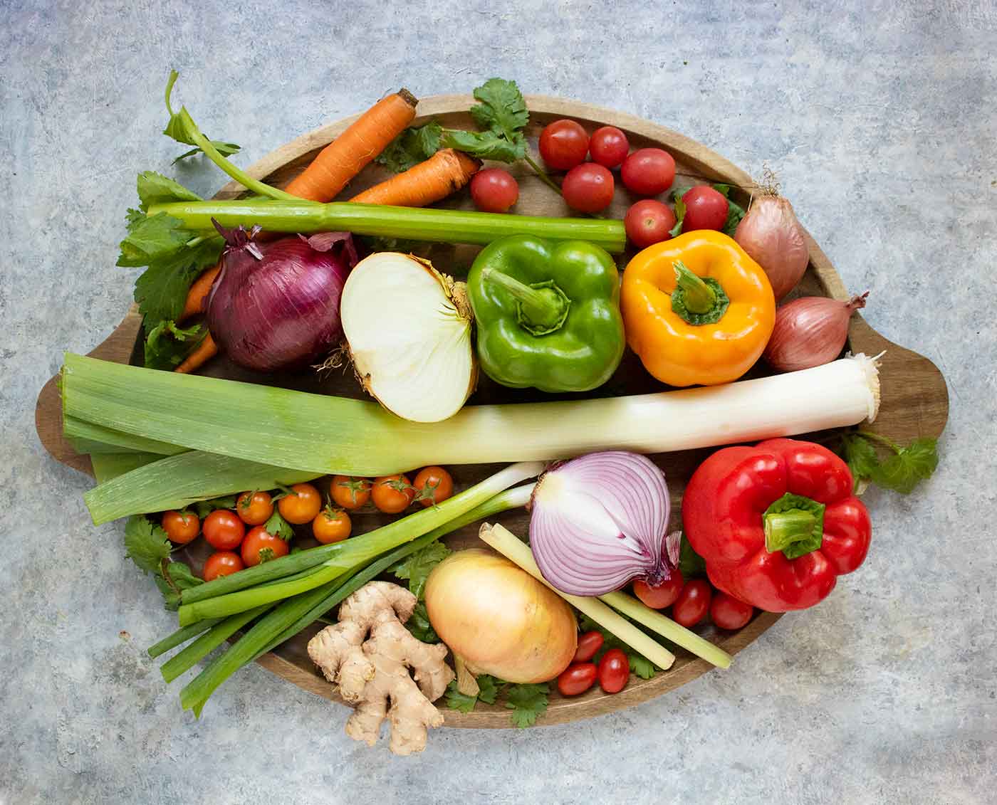 A variety of vegetables on a wooden platter.
