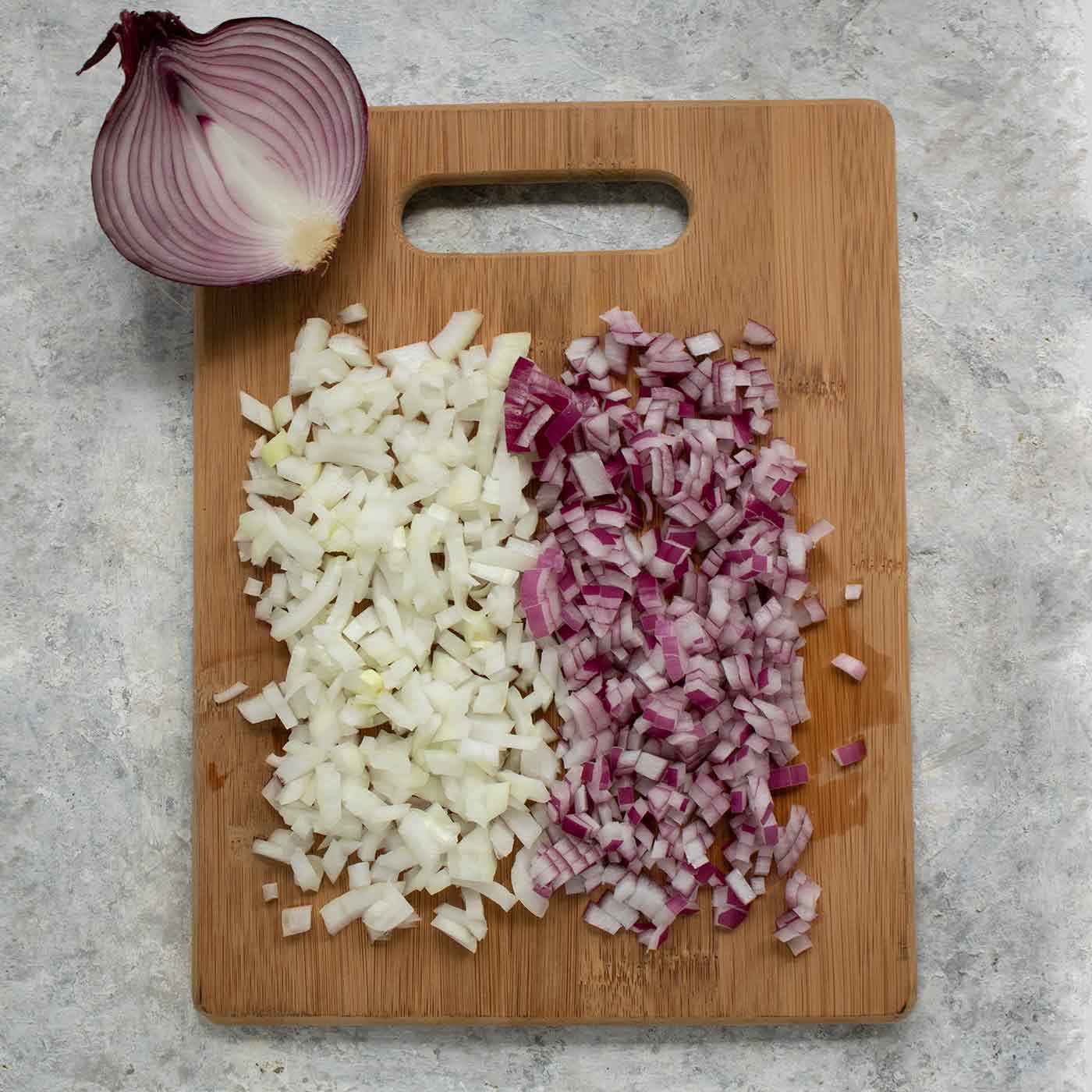 Chopped white onions and red onions on a wooden cutting board.