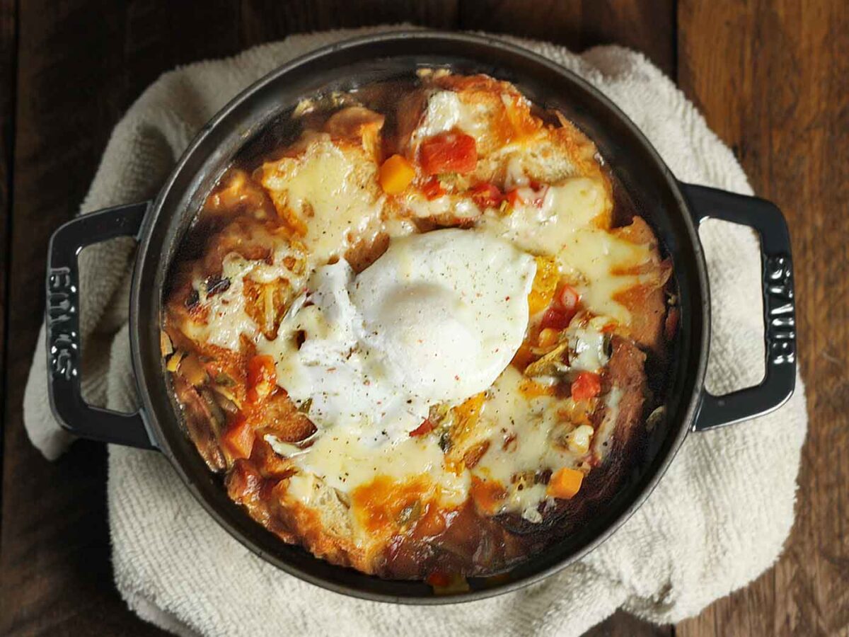 Autumn Vegetable Soup in a black Dutch oven, topped with an egg.