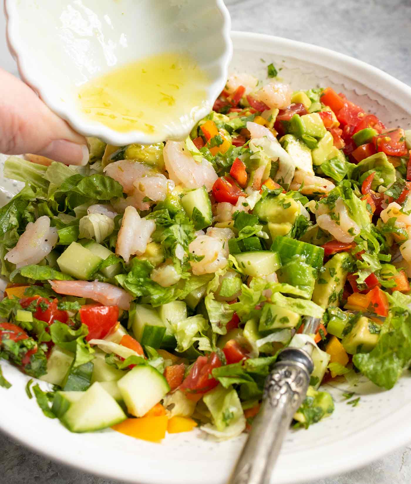 Pouring lime juice dressing on Avocado Shrimp Salsa Salad.