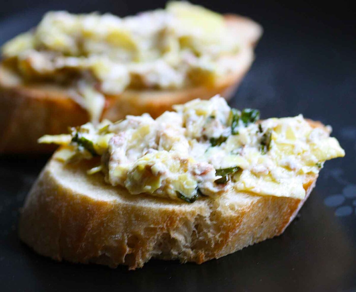 Two crostinis with Baked Artichoke Olive Dip