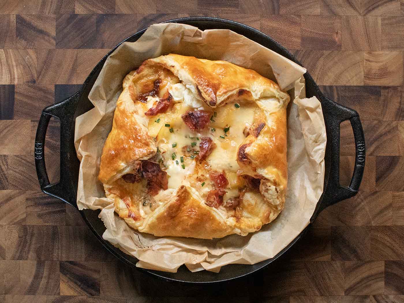 Overhead view of Bake Cheesy Puff Pastry with Crispy Prosciutto in a cast iron skillet.