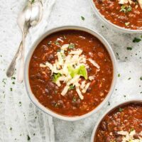 Three bowls of BBQ Black Bean Soup topped with shredded cheese