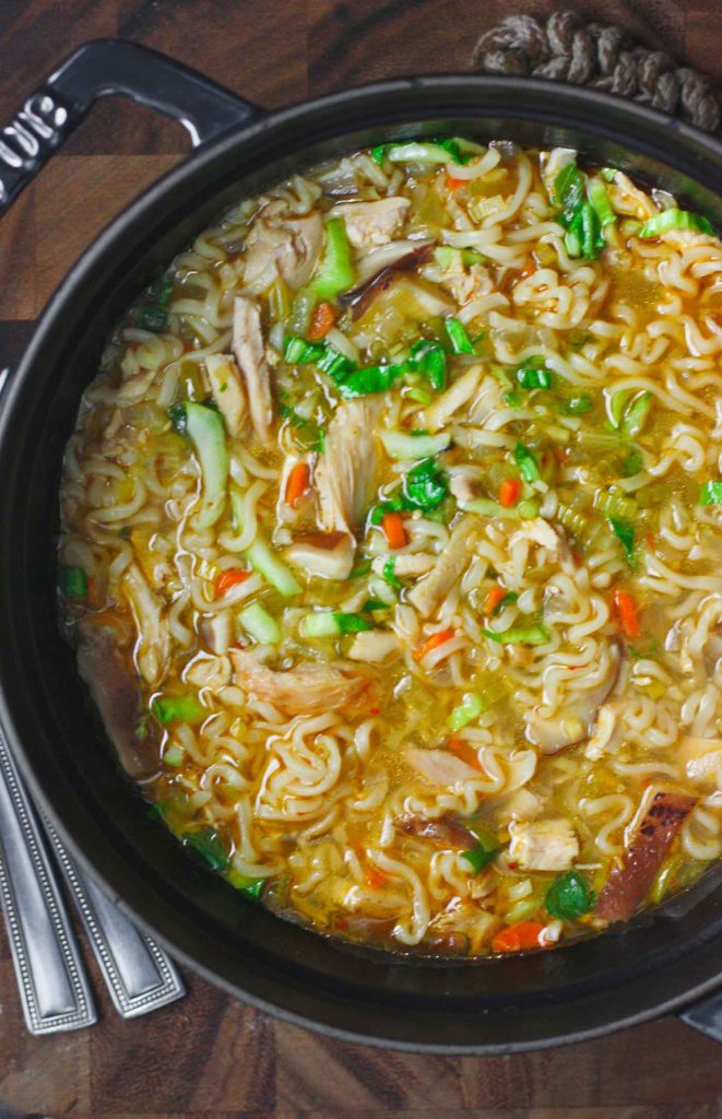 A black Dutch oven filled with Thai Ramen Noodle Chicken Soup