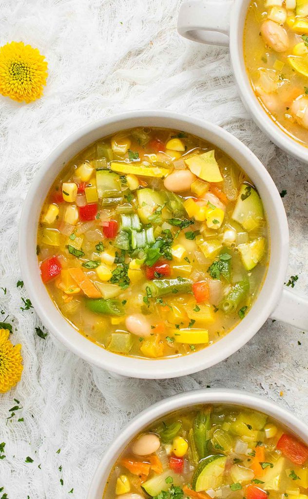 A light grey mug of Summer Minestrone soup.