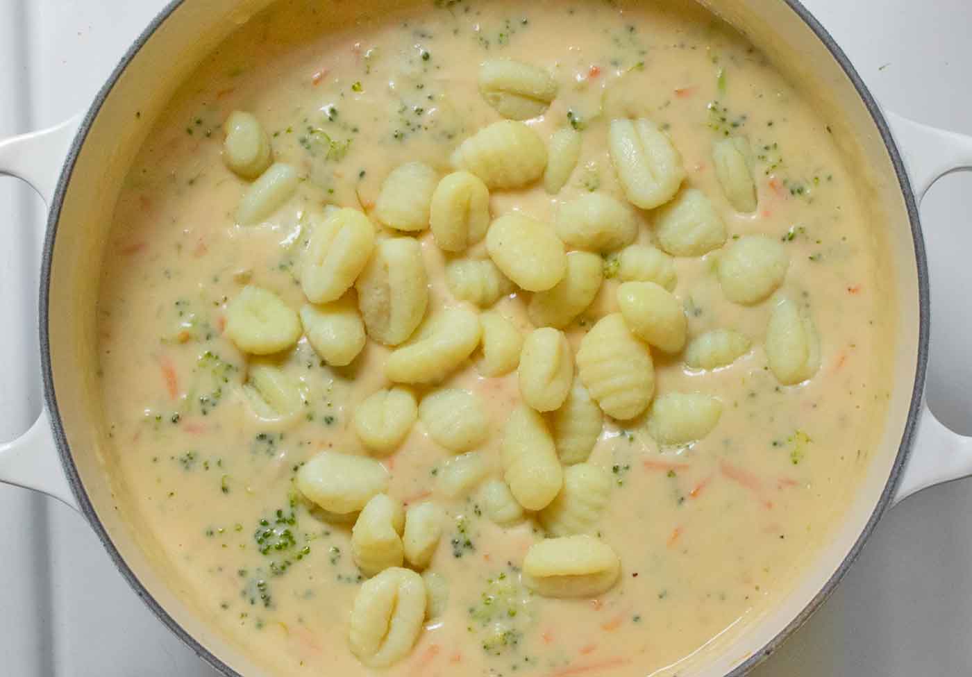 Overhead shot adding the cooked gnocchi to the soup.