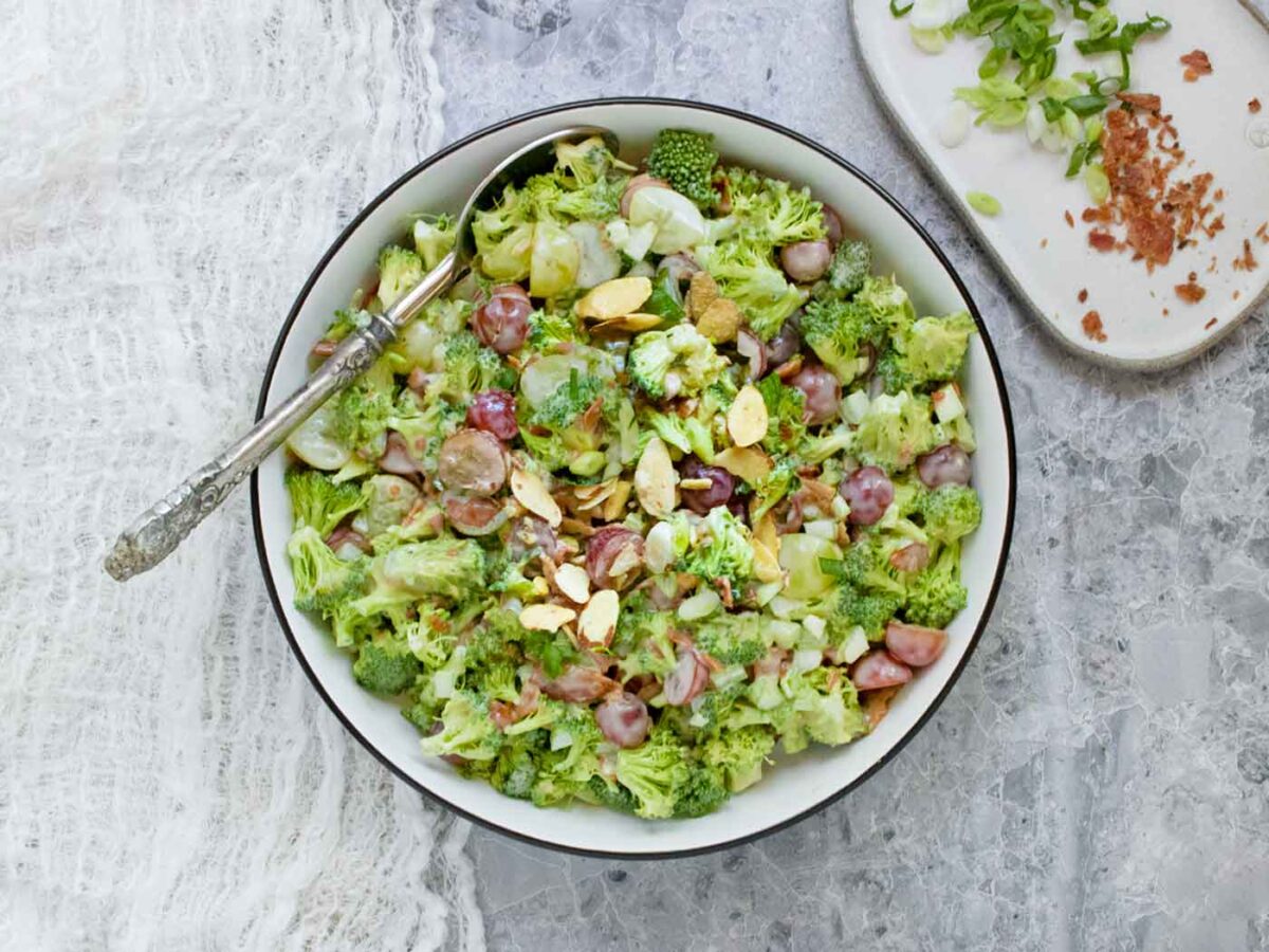Overhead view of Broccoli Grape Salad in a white bowl with a black rim.