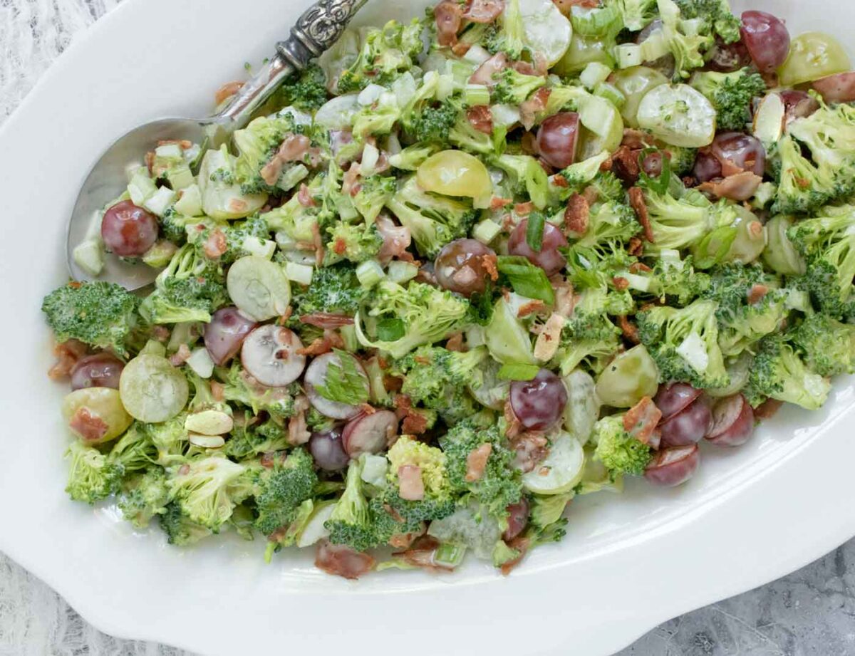 Broccoli Grape Salad on a white serving platter with a serving spoon.