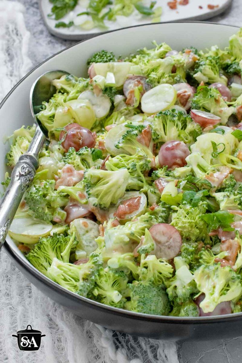 Pinterest pin image for Broccoli Grape Salad recipe, featuring a side-angled view of the salad in a bowl.