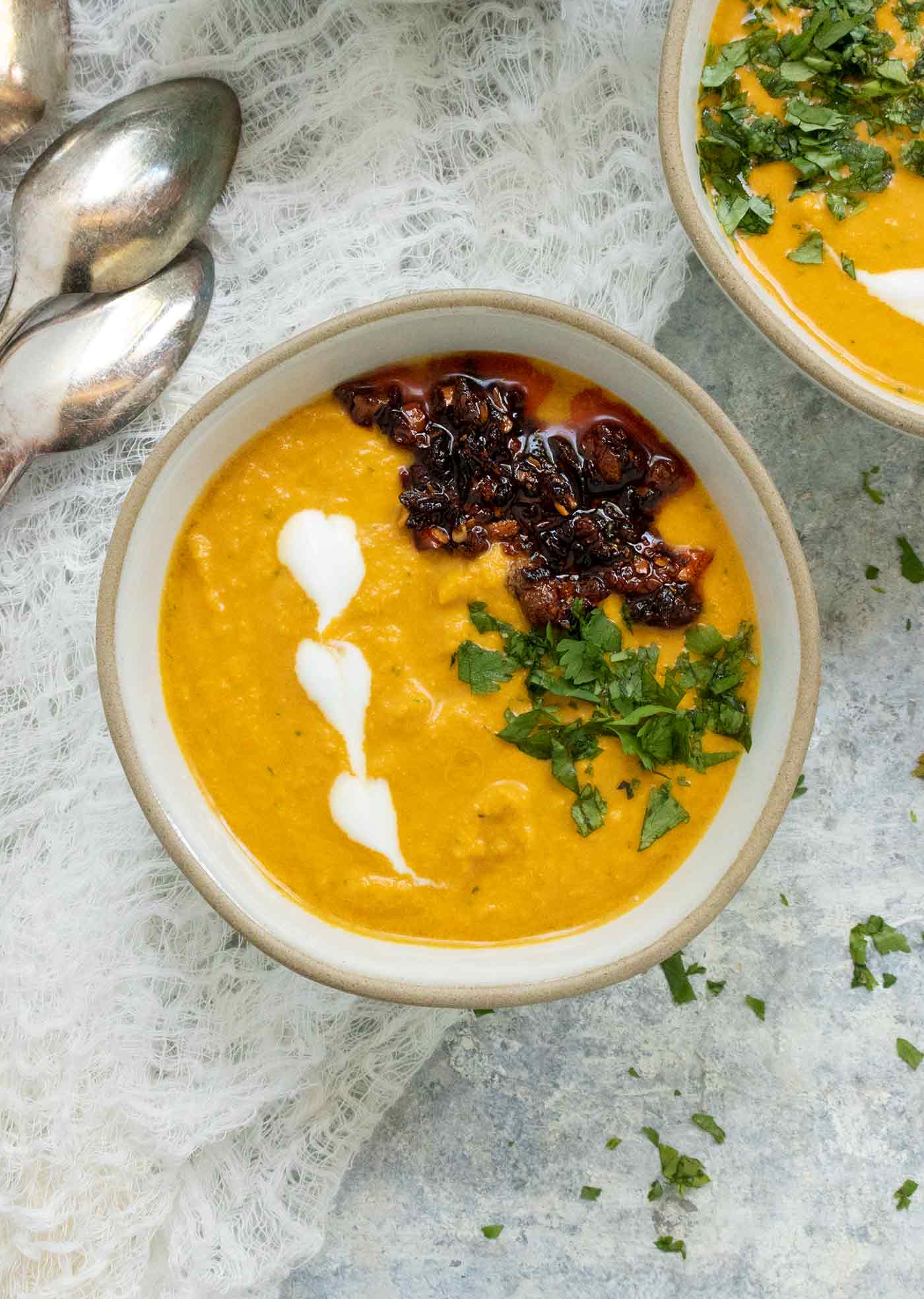 A bowl of Carrot Gazpacho garnished with chile crisp and chopped cilantro.