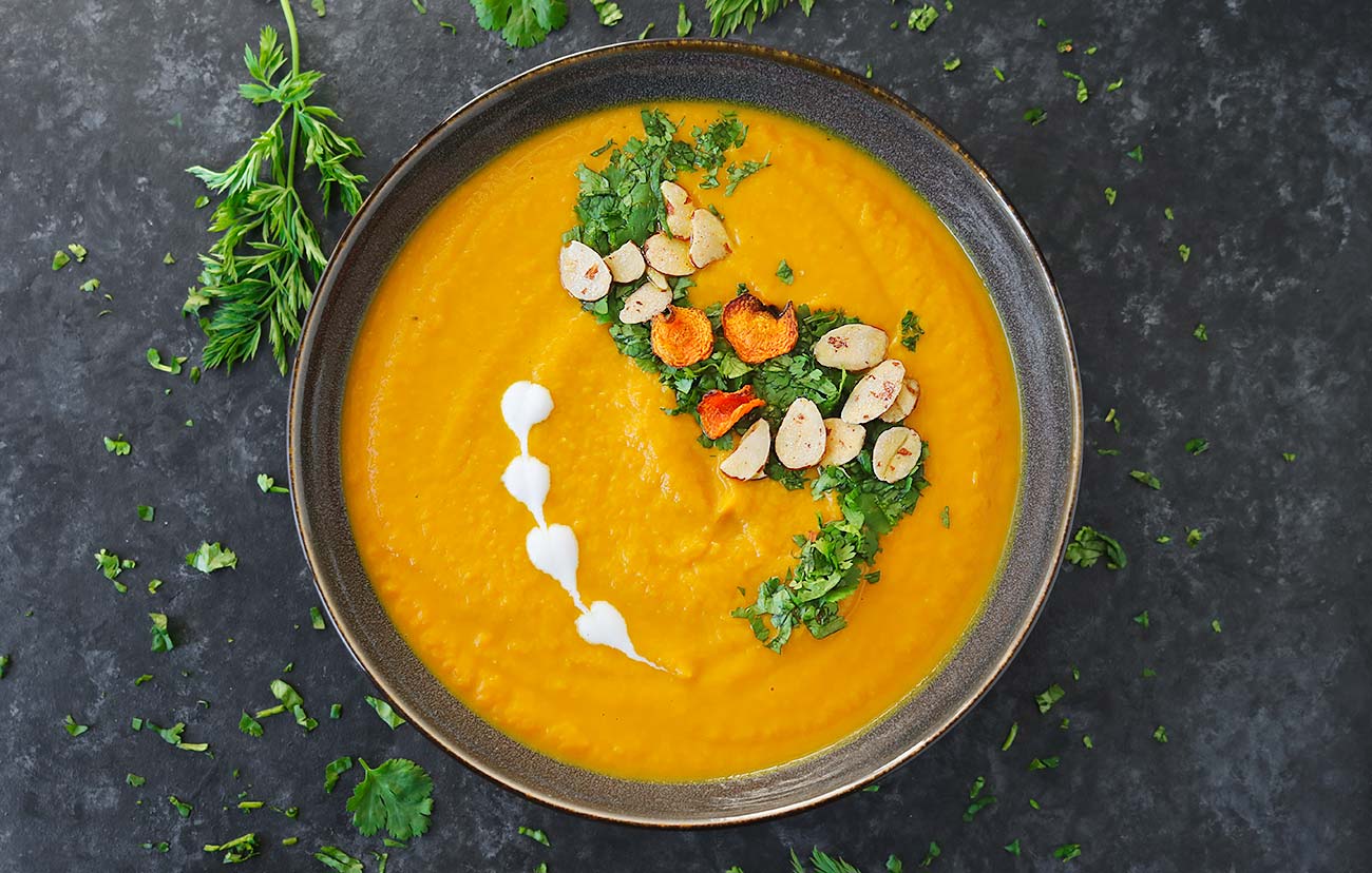 Overhead view of Carrot Turmeric Miso Soup in a dark gray bowl.