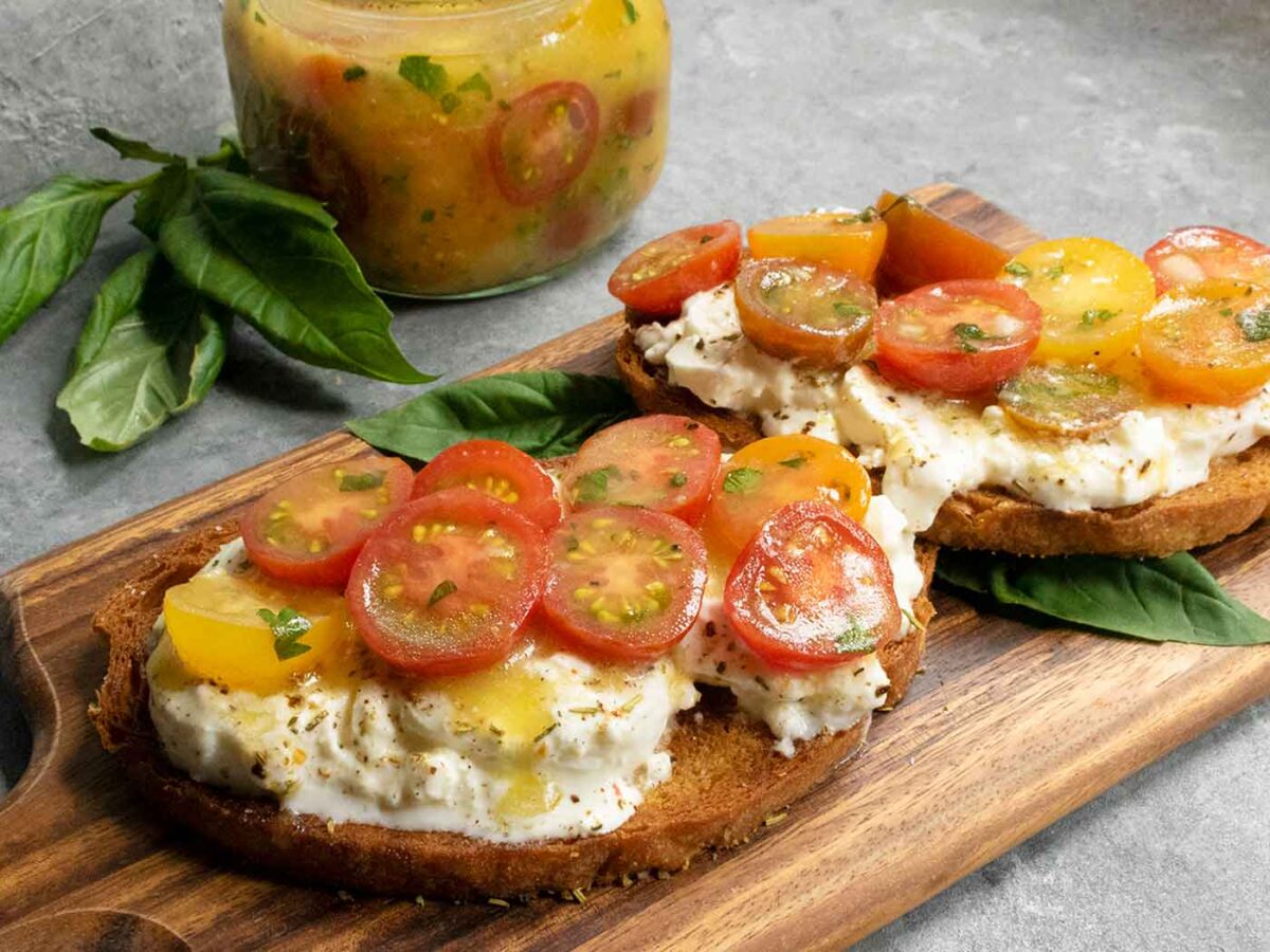 Two slices of Cherry Tomato Bruschetta on a wooden serving board.