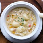 Chicken Gnocchi Soup in a white bowl with a spoon.