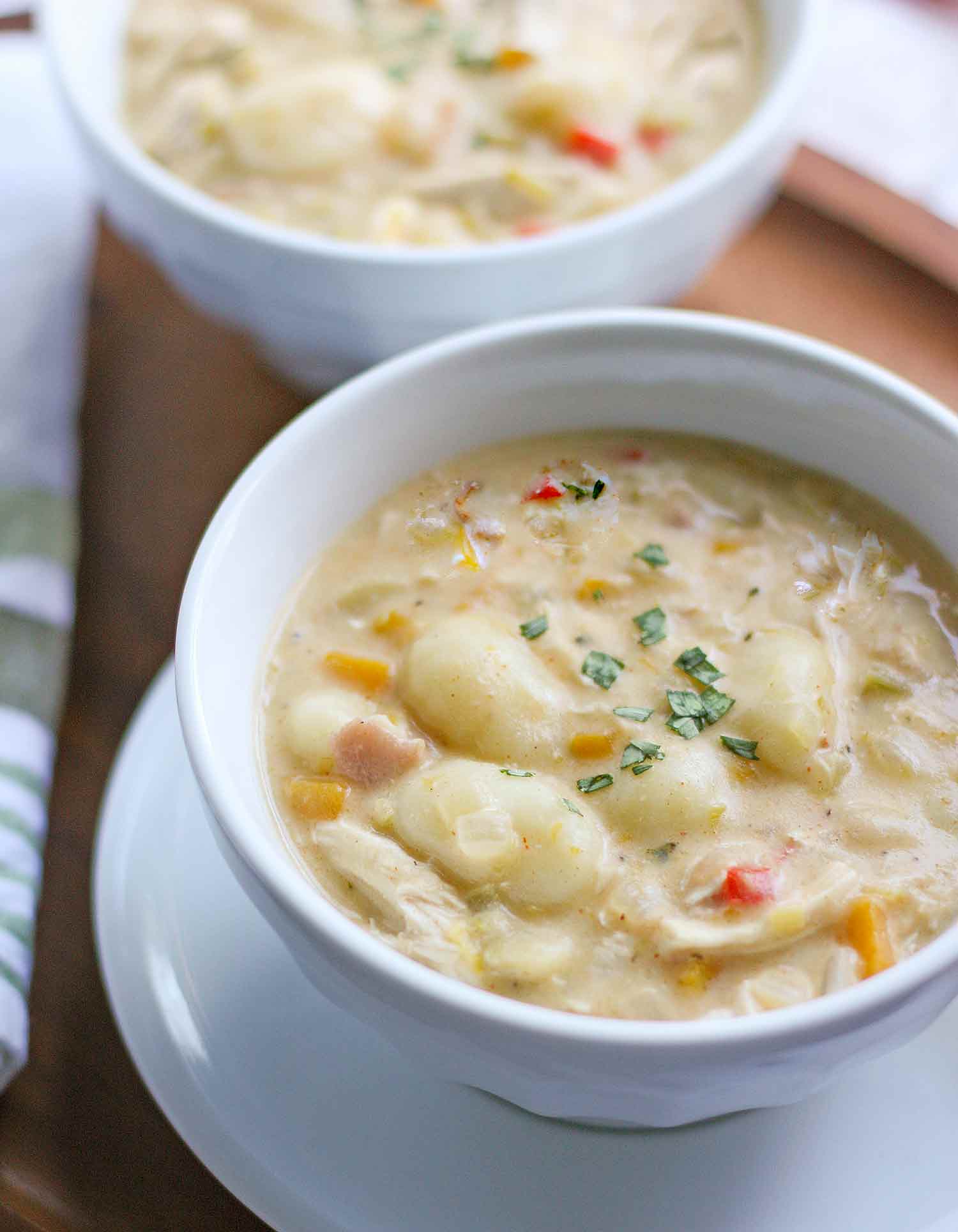 Angled view of two bowls of Chicken Gnocchi Soup.