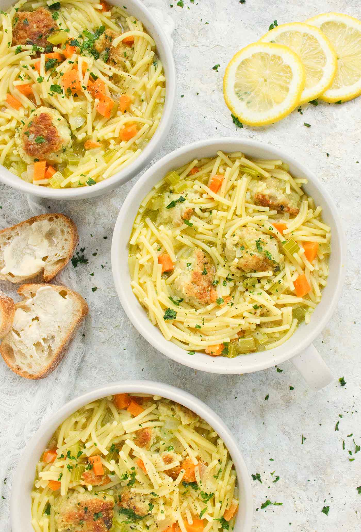 Three bowls of Chicken Meatball Noodle Soup with a side of crusty bread