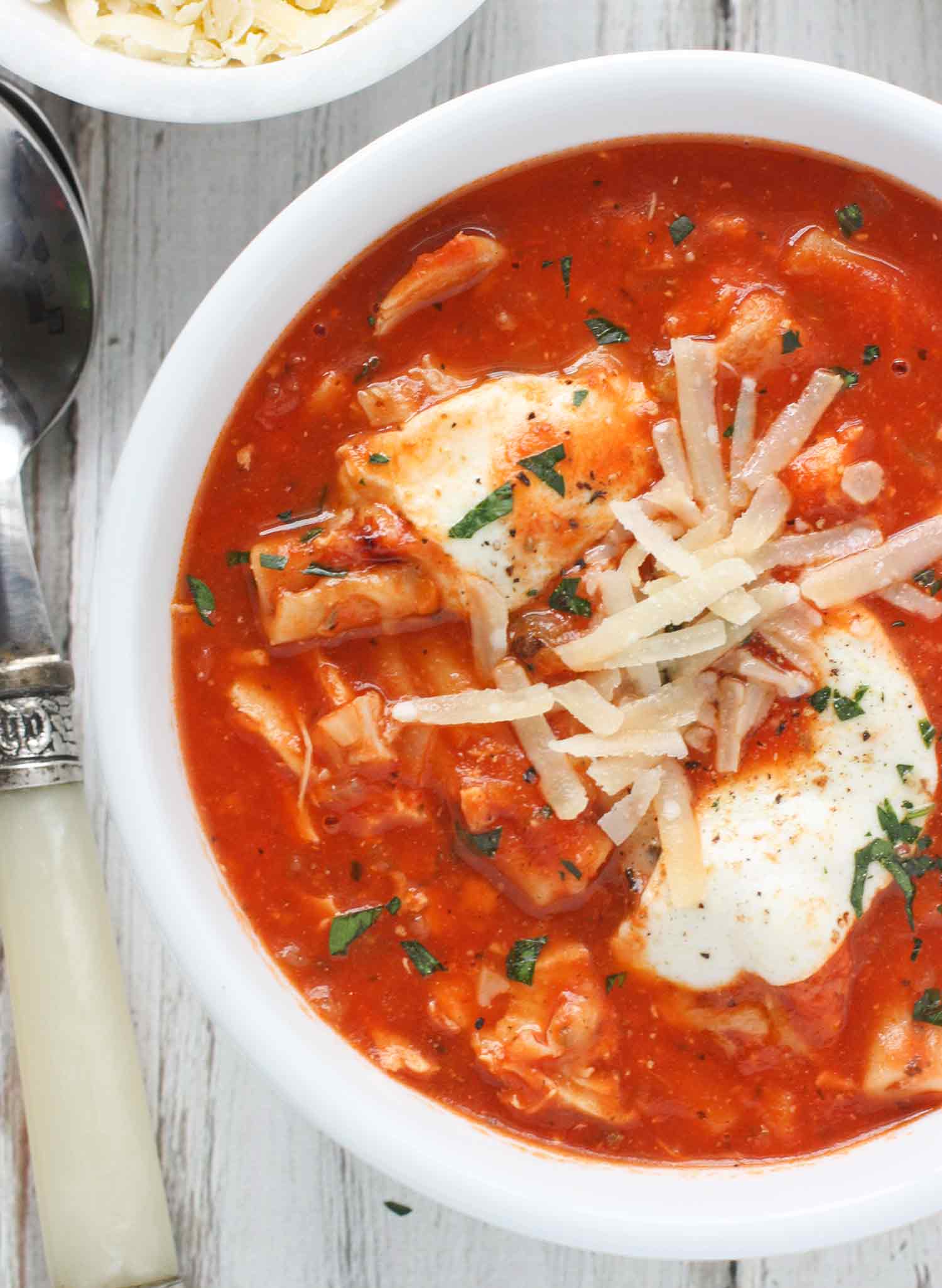 Close up of a bowl of Chicken Parmesan Soup with a spoon.