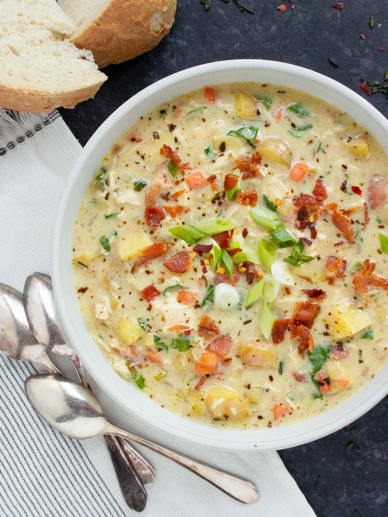 View from above of a bowl of Chicken Potato Soup, with spoons to the side.