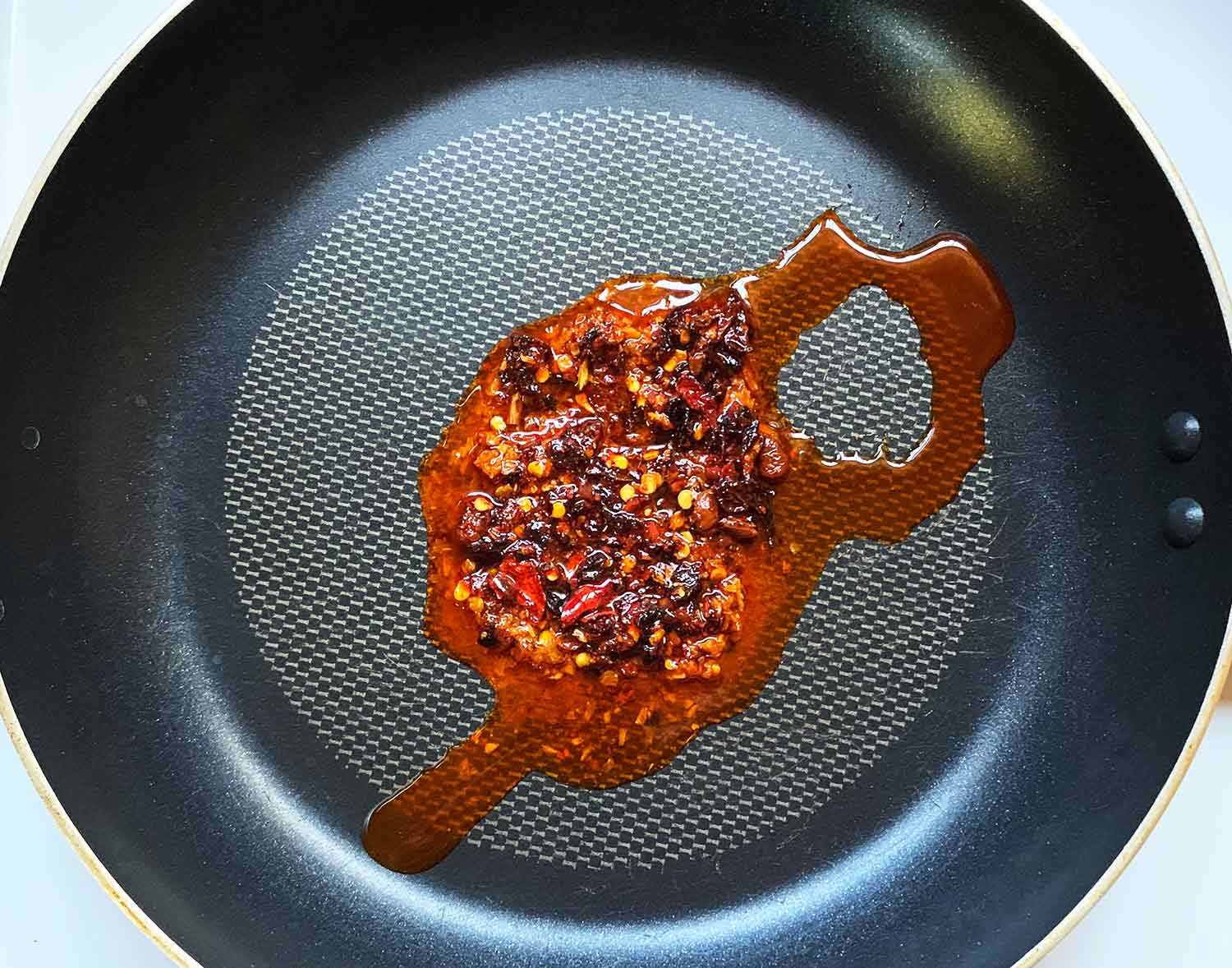 Warming up the chili crisp and sesame oil in the skillet.