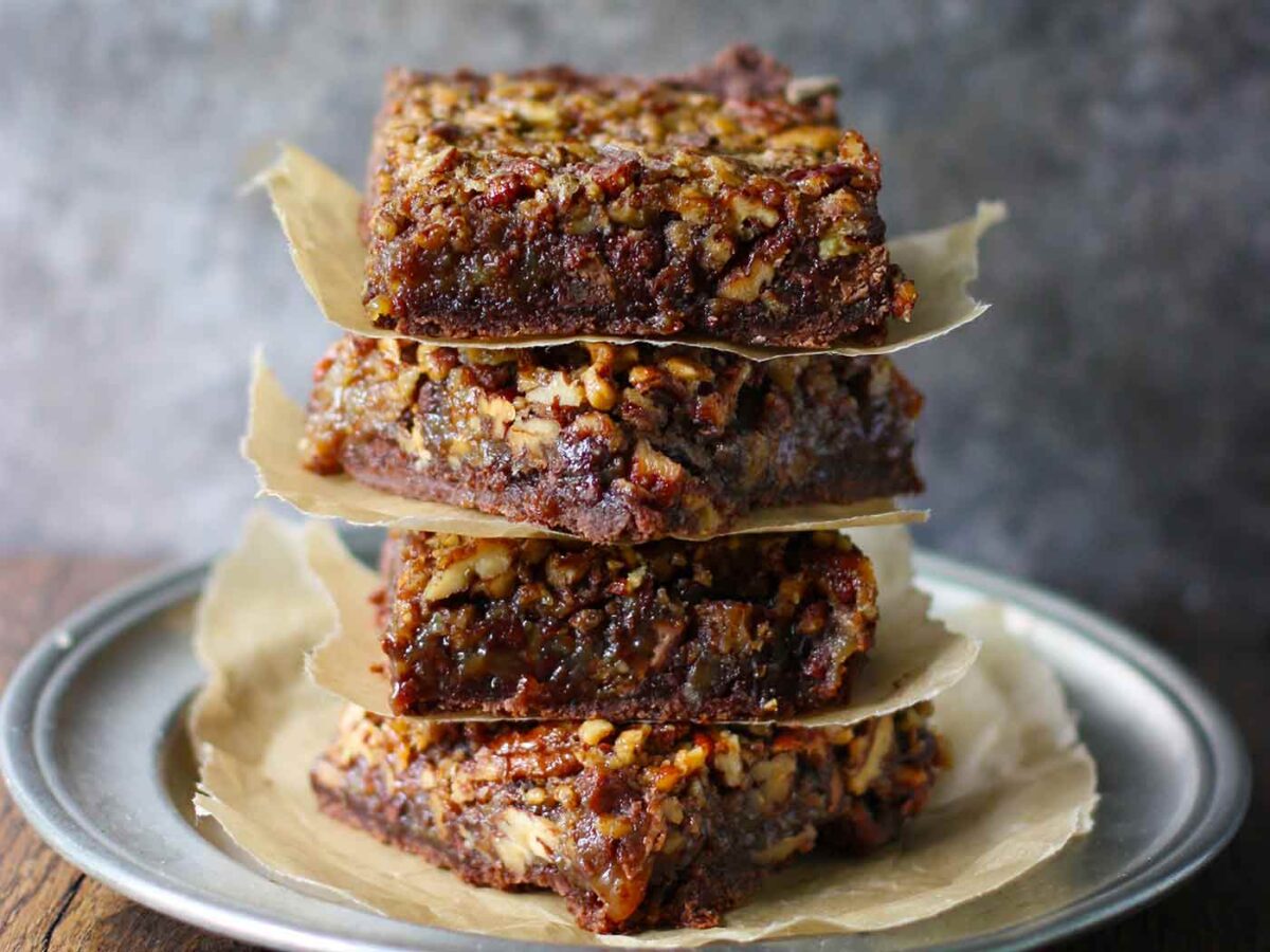 Chocolate Caramel Pecan Pie Bars stacked on a plate.