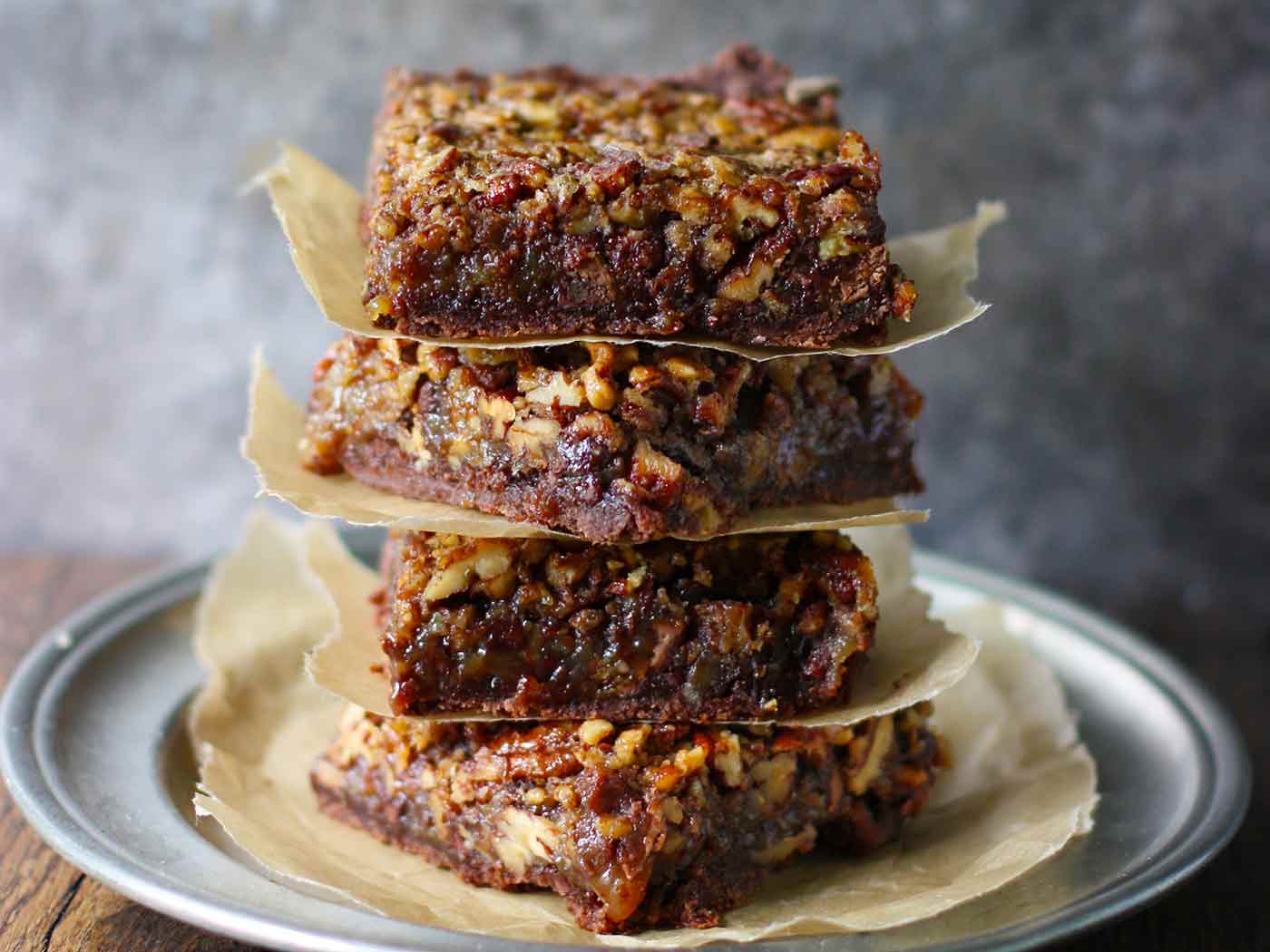 Chocolate Caramel Pecan Pie Bars stacked on a plate.