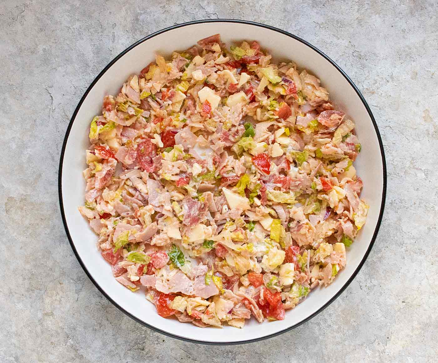 The ingredients of the grinder chopped and ready to use, in a white bowl with a black rim.