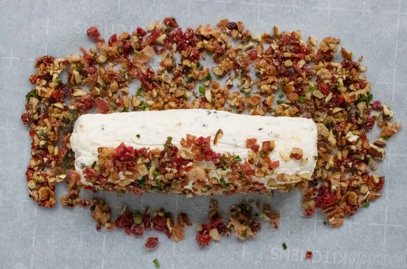 Step 4: Photo showing the cream cheese log being rolled in the toppings.