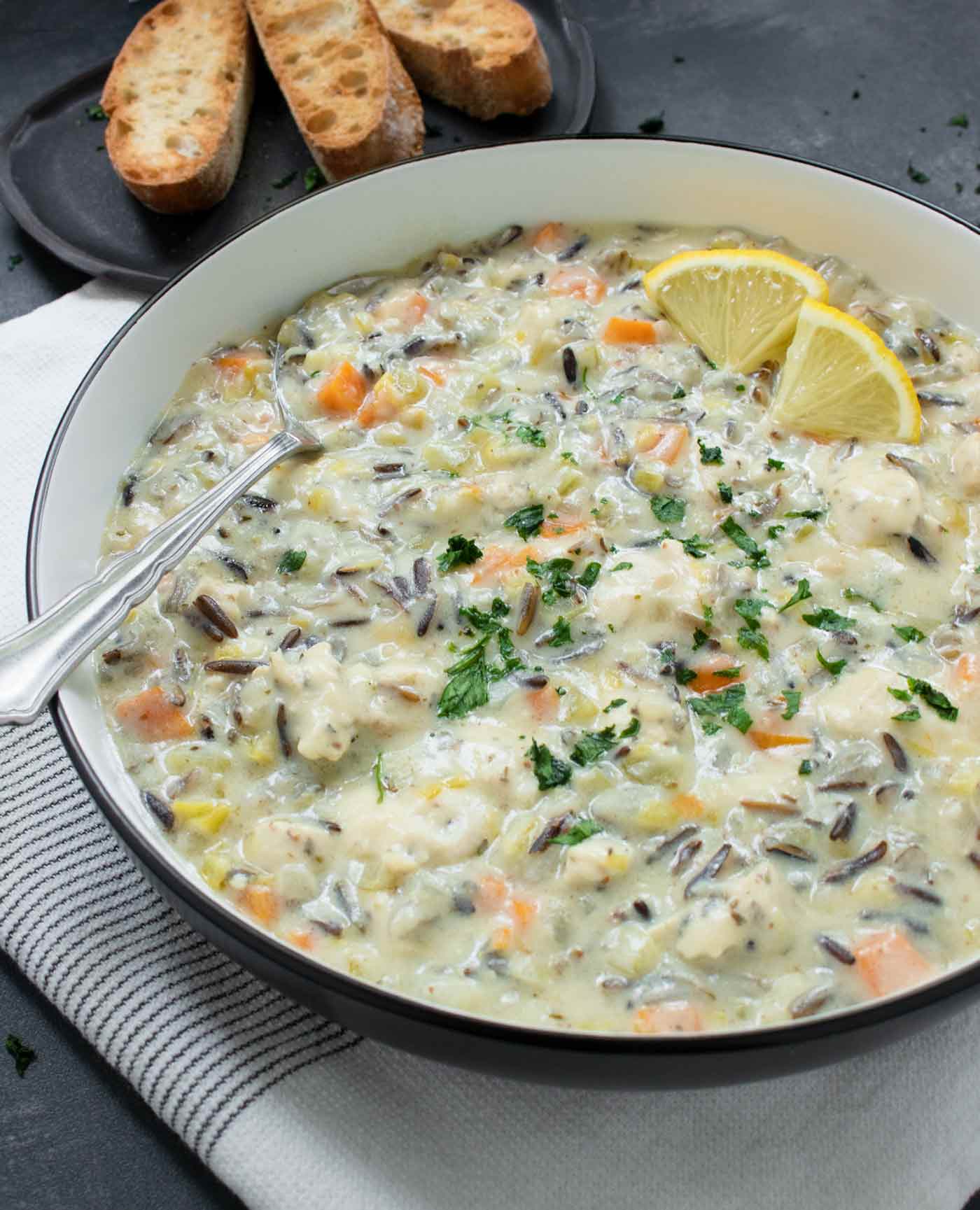 Side angled view of chicken wild rice soup in a bowl with a spoon.