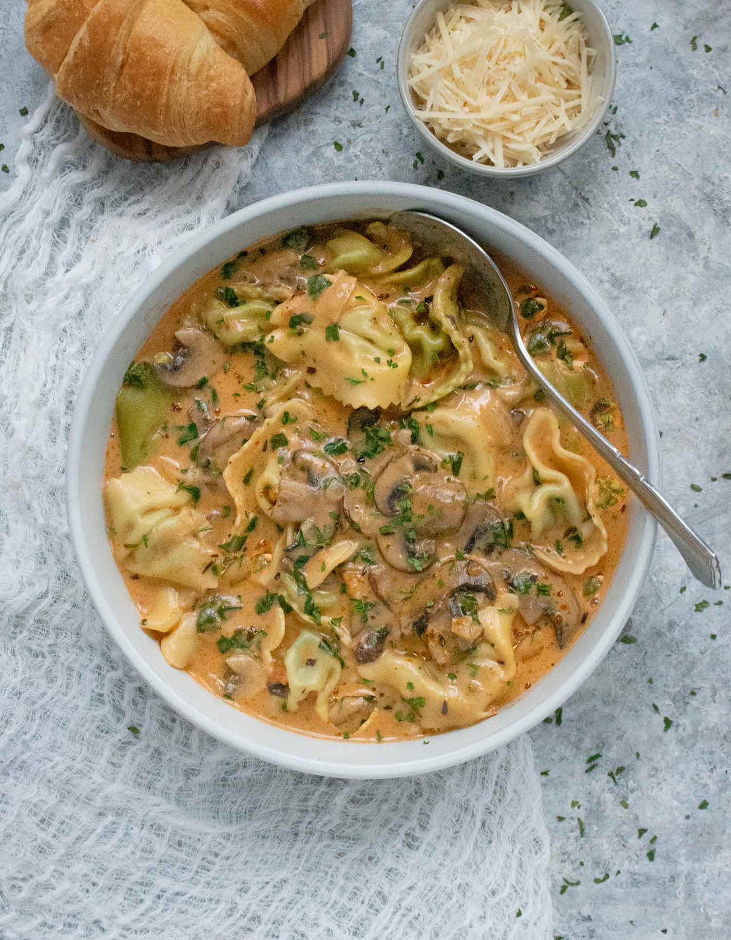Creamy Mushroom Tortellini Soup in a white bowl with a spoon.
