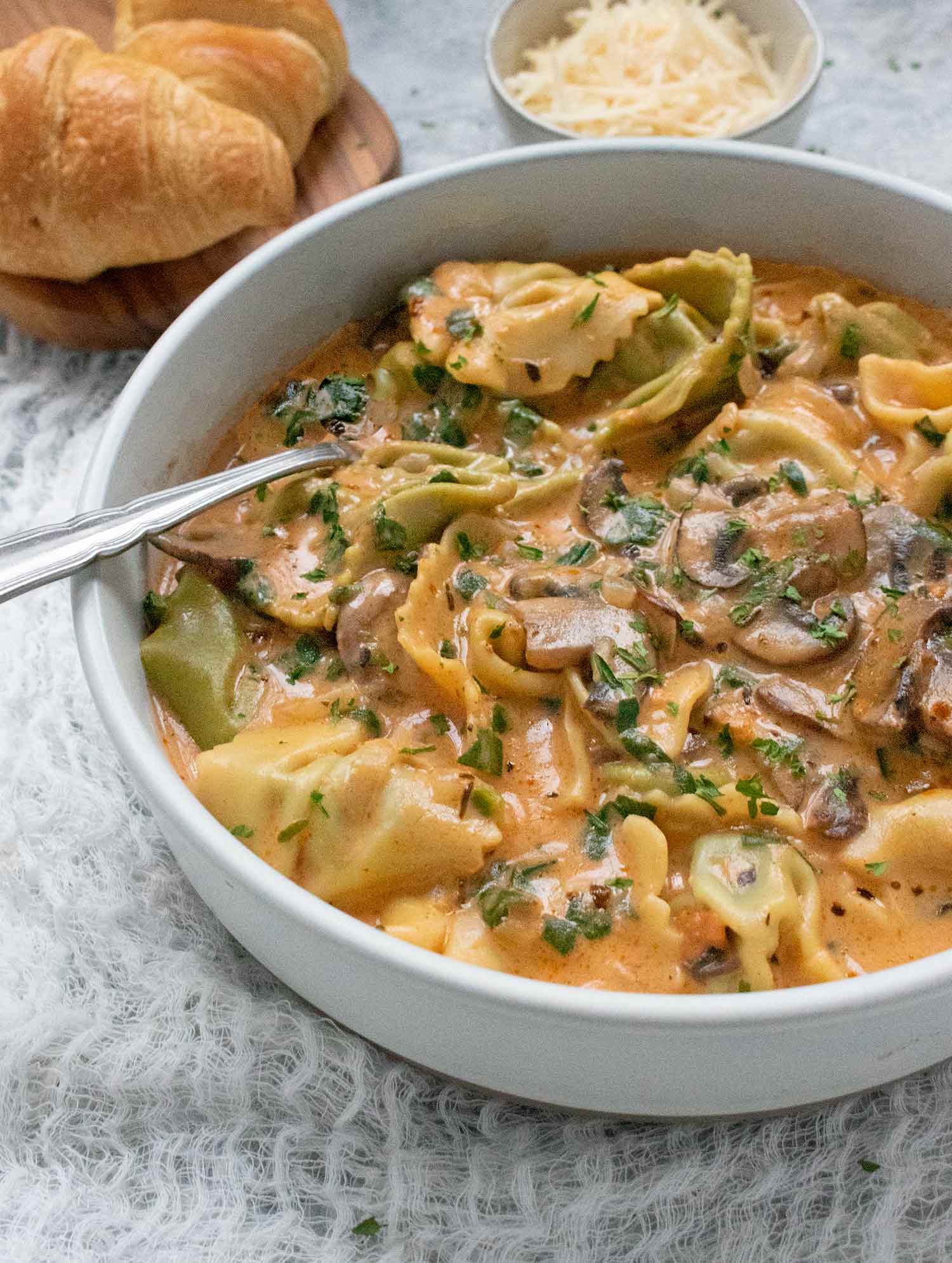 Side view of Creamy Mushroom Tortellini Soup in a white bowl.