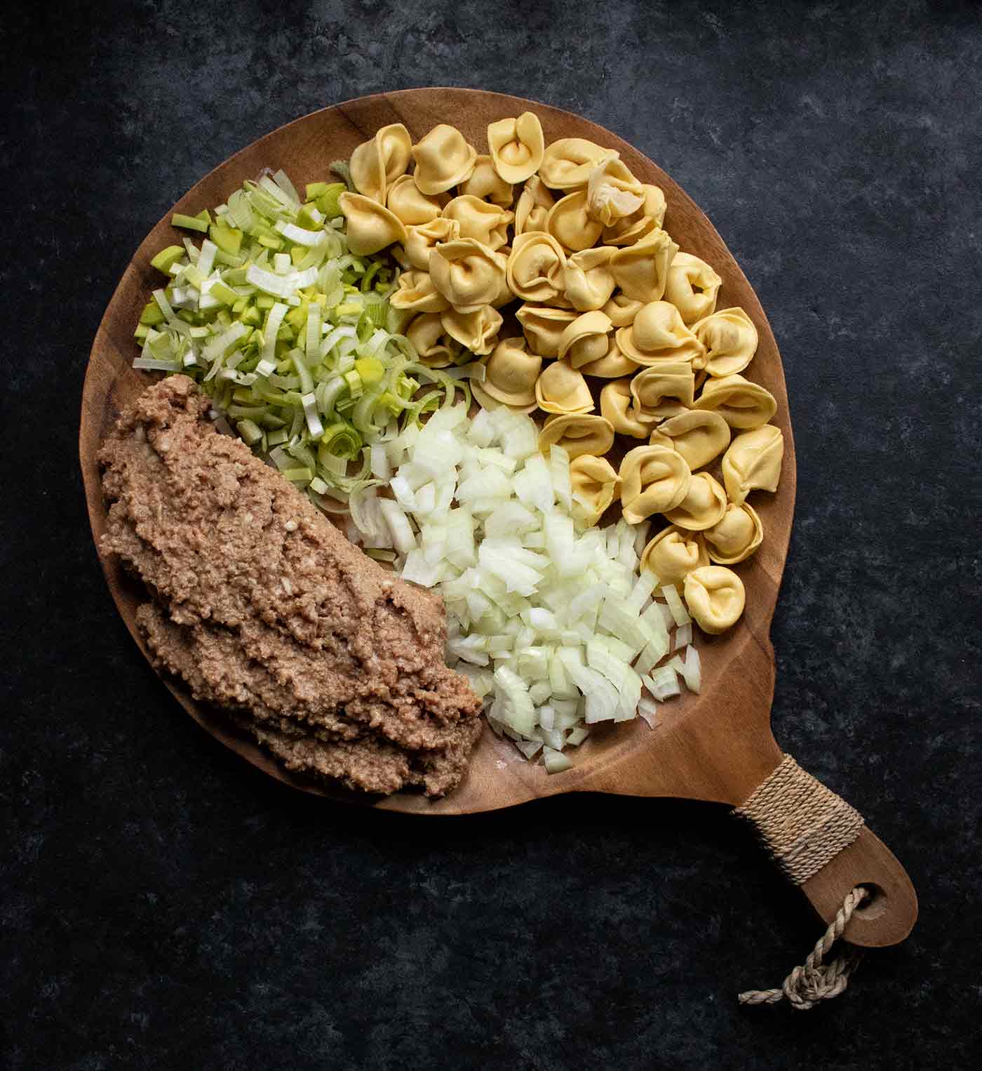 Ingredients for Creamy Tortellini Soup on a wooden serving board.