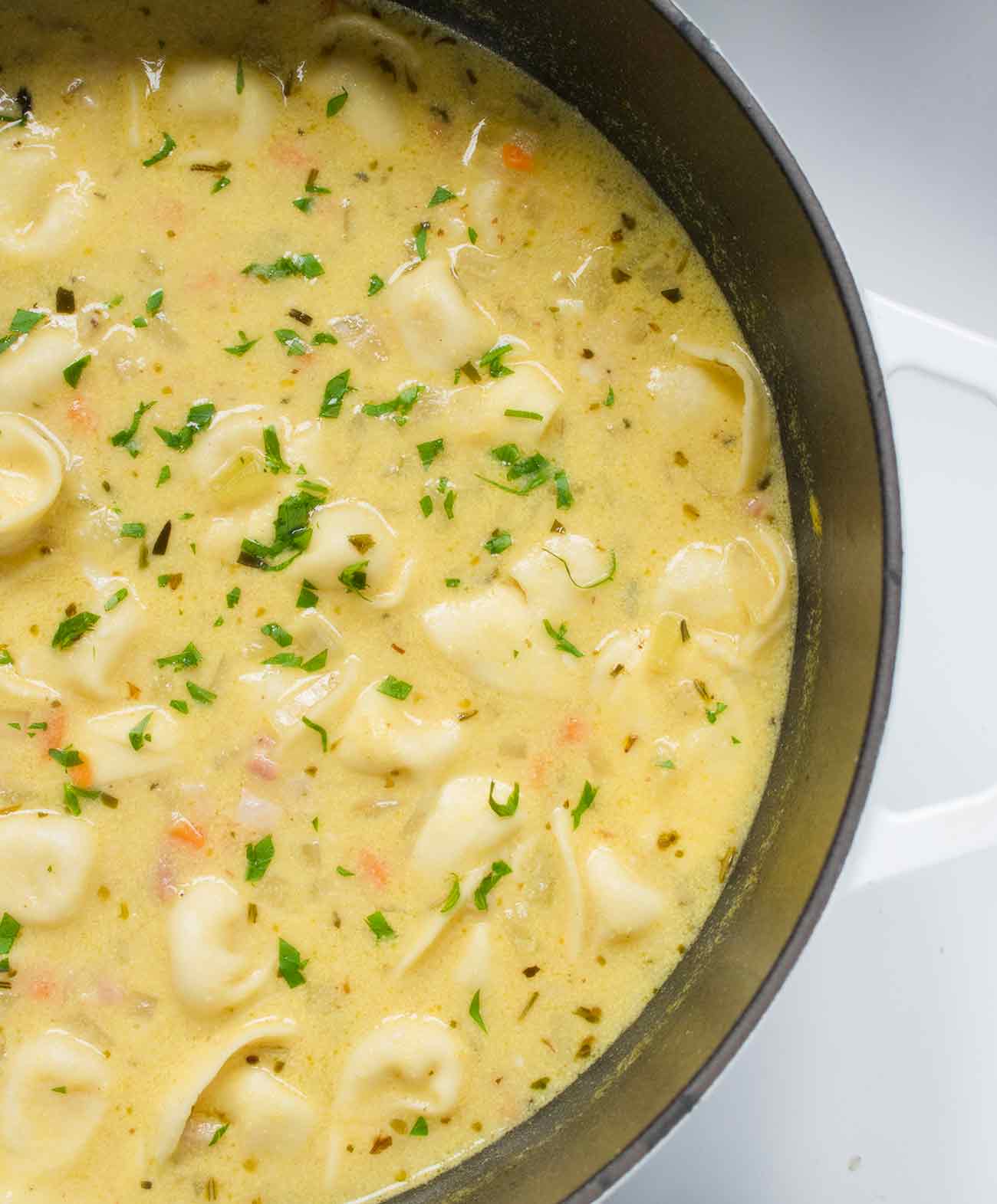 Creamy white bean tortellini soup cooking in a pot.