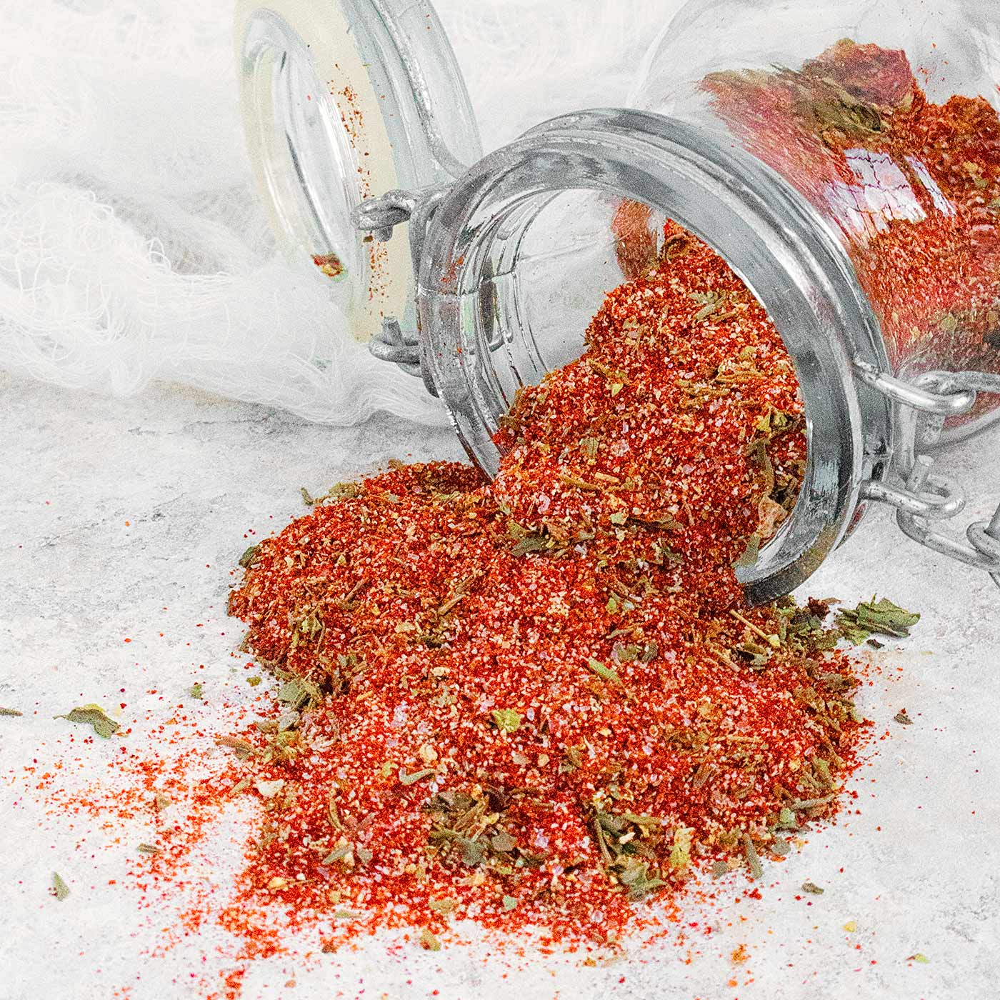 Homemade Creole seasoning blend spilling out of a glass jar.