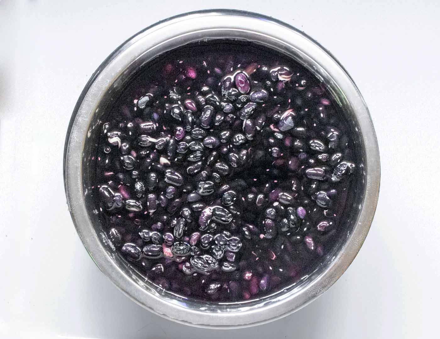 Black beans finishing up soaking in water in a bowl, ready to cook.