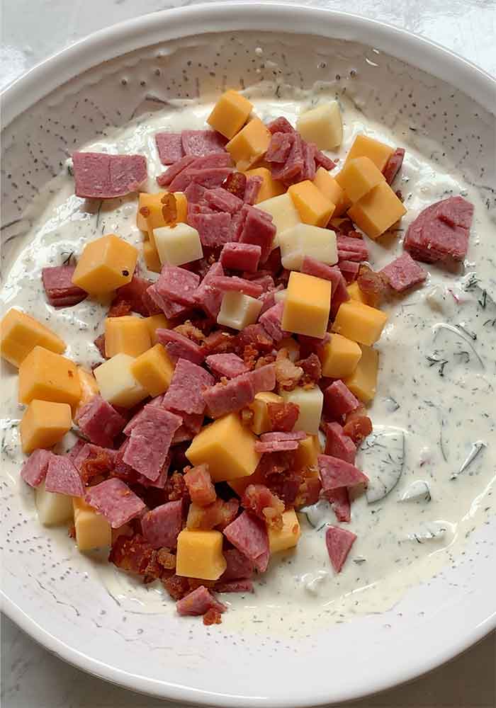 Folding in the cheeses and cured meats.