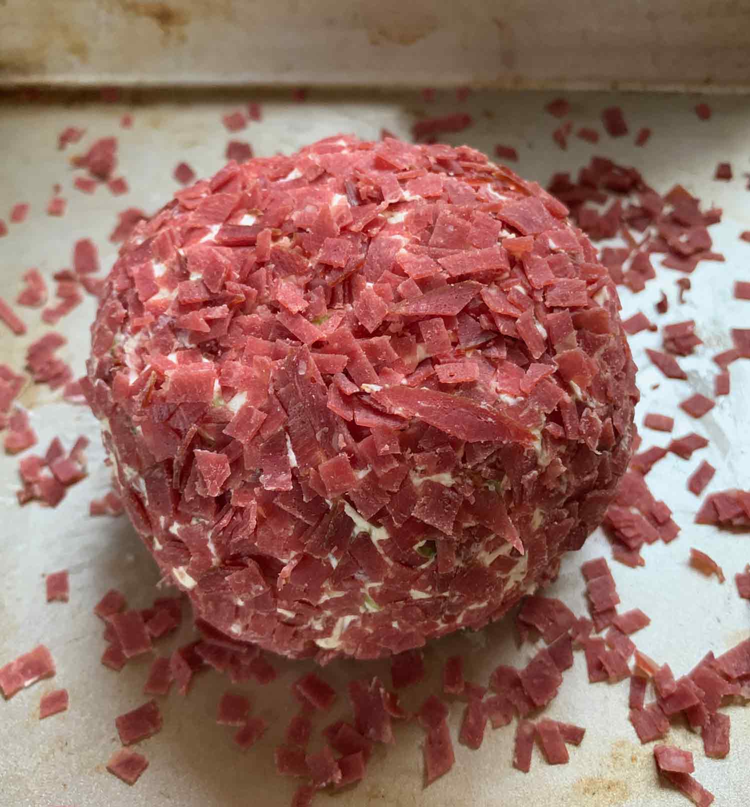 Rolling the cheese ball in the dried beef, in a shallow pan.