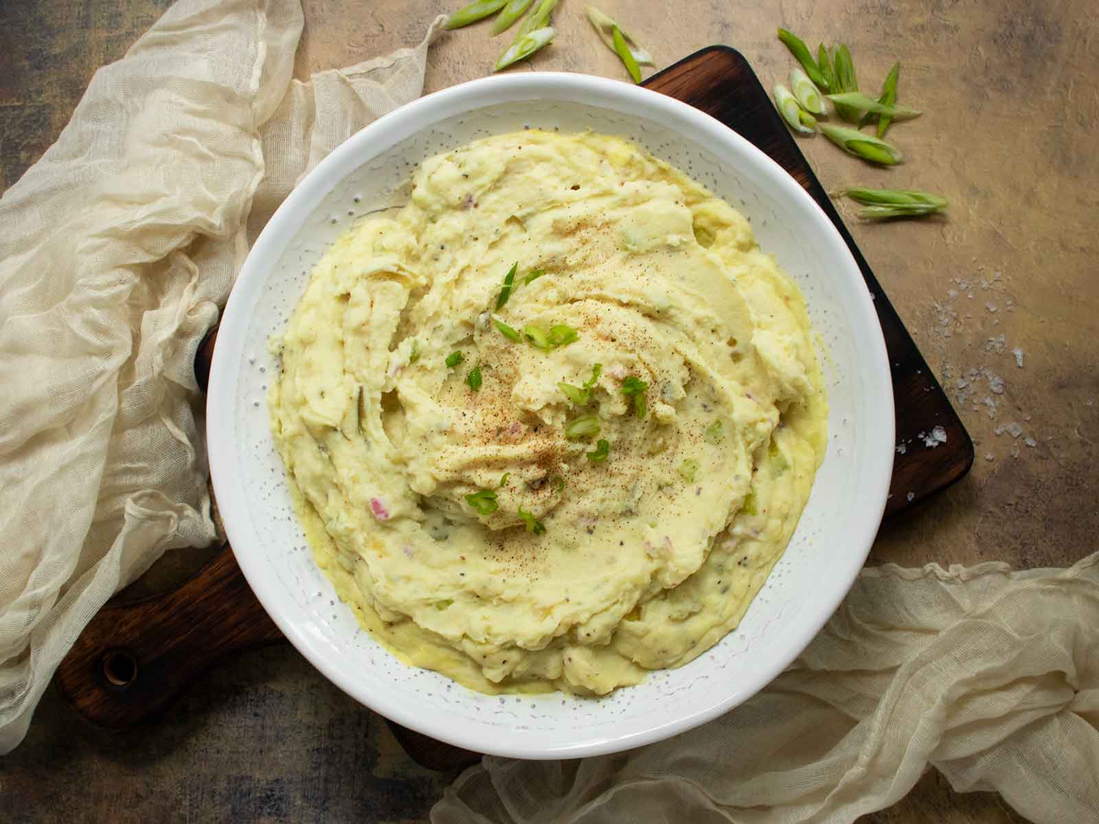 Easy Mashed Potato Salad in a white bowl on a serving board.