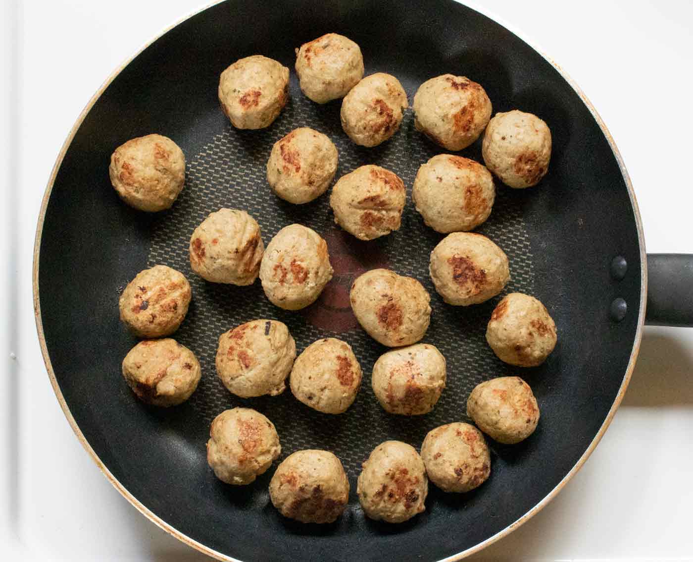 Seared meatballs in a skillet.