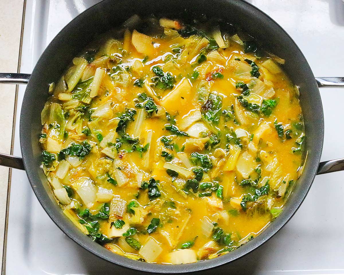 Vegetables and leafy greens cooking in the soup pot.