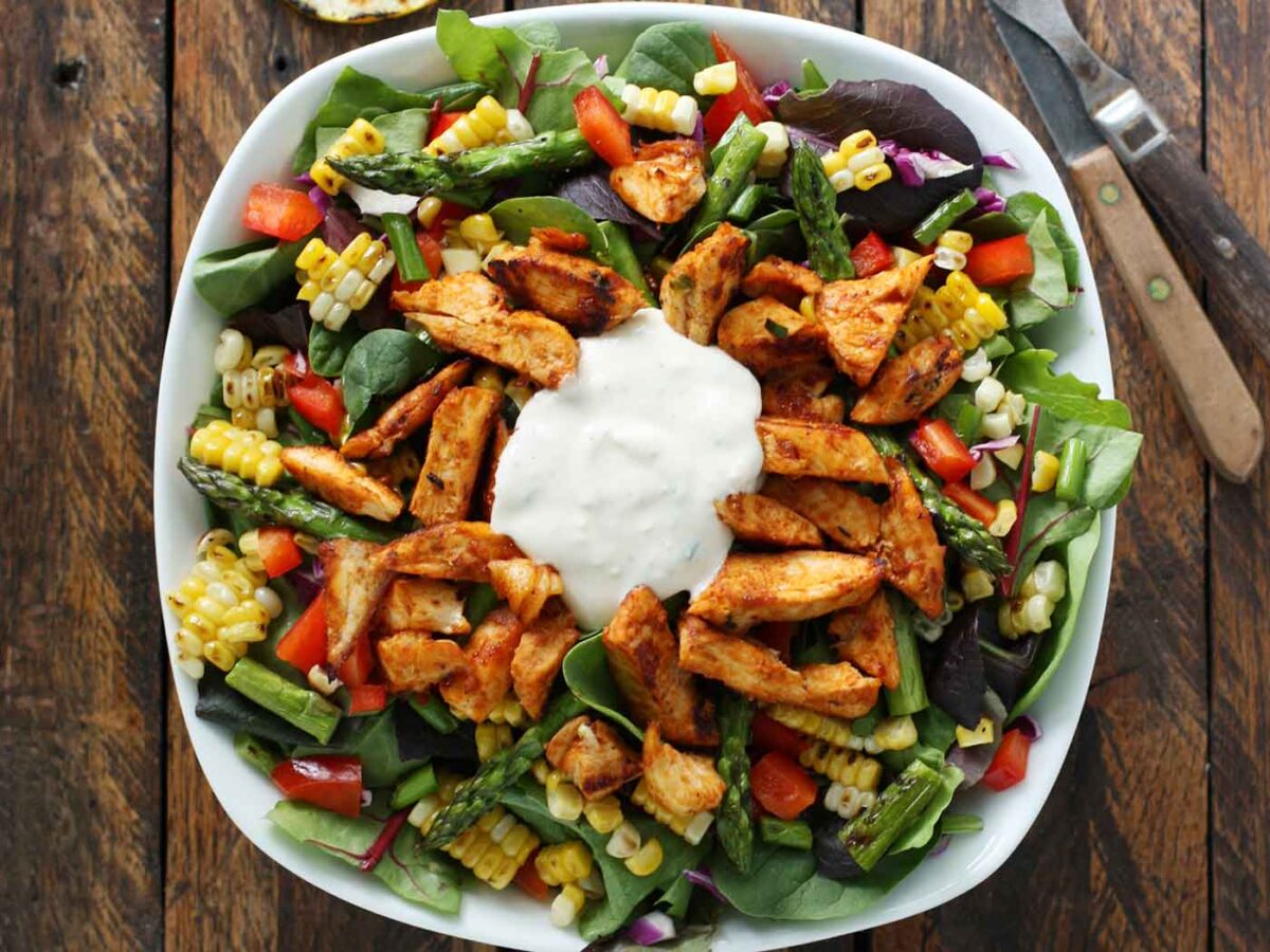 Overhead view of Grilled BBQ Blue Cheese Chicken Salad in a squarish white bowl.
