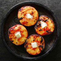 Grilled peaches with a pat of butter, on a tin