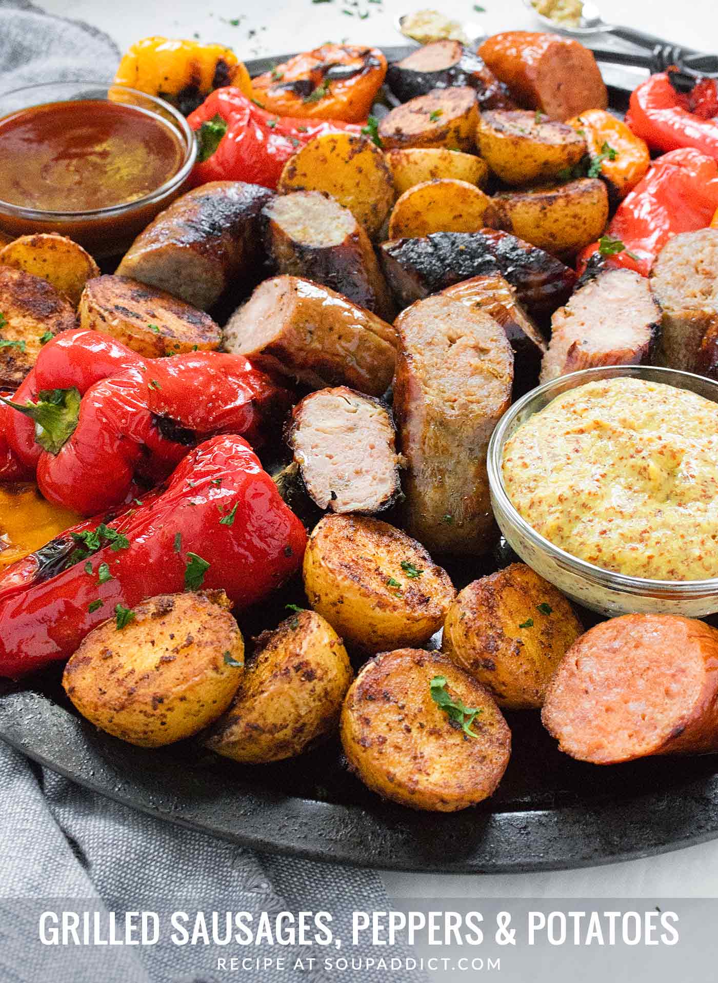 Grilled Sausages, Peppers & Potatoes on a platter with dipping sauces