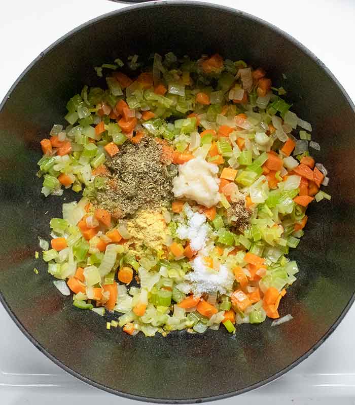 Adding the garlic and other seasonings to the aromatic vegetables.