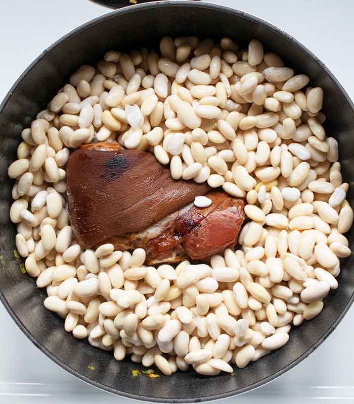 Adding the beans and smoked ham hock to the pot.