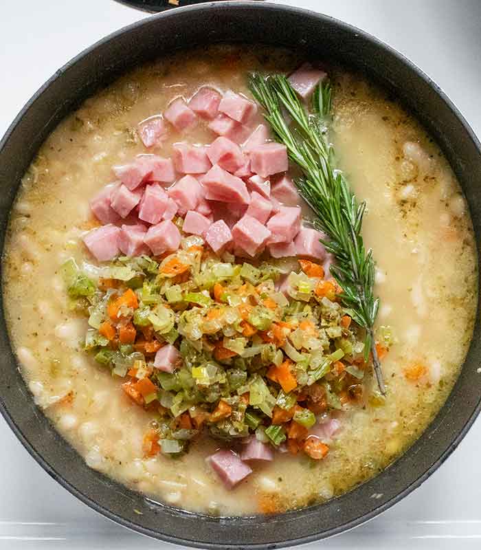 Adding the cooked ham and returning the aromatic veggies to the soup, to finish cooking.