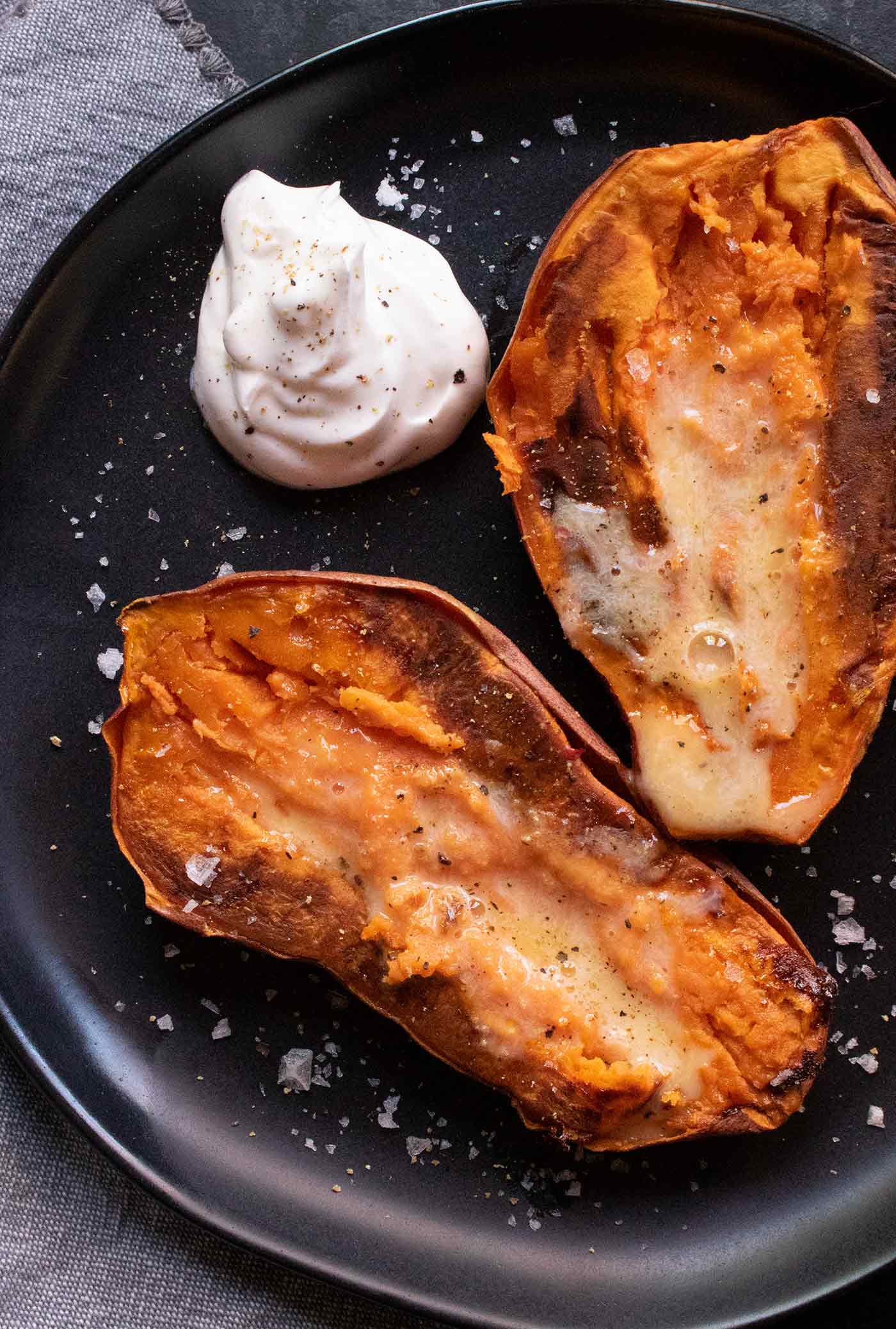 Close up of a half of a baked sweet potato on a black plate