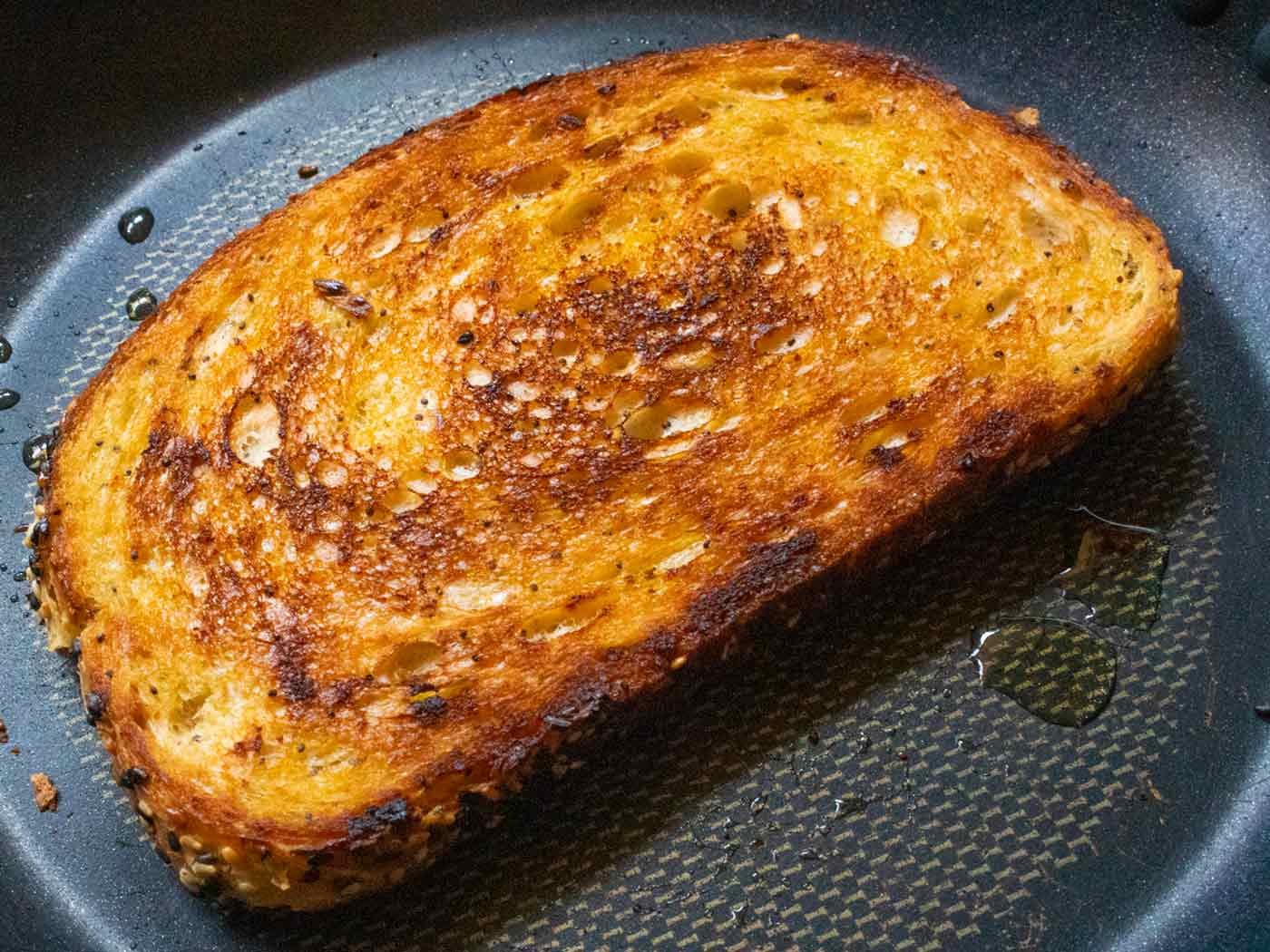 A slice of fully cooked fried toast in a skillet, beautifully golden brown and ready to serve.