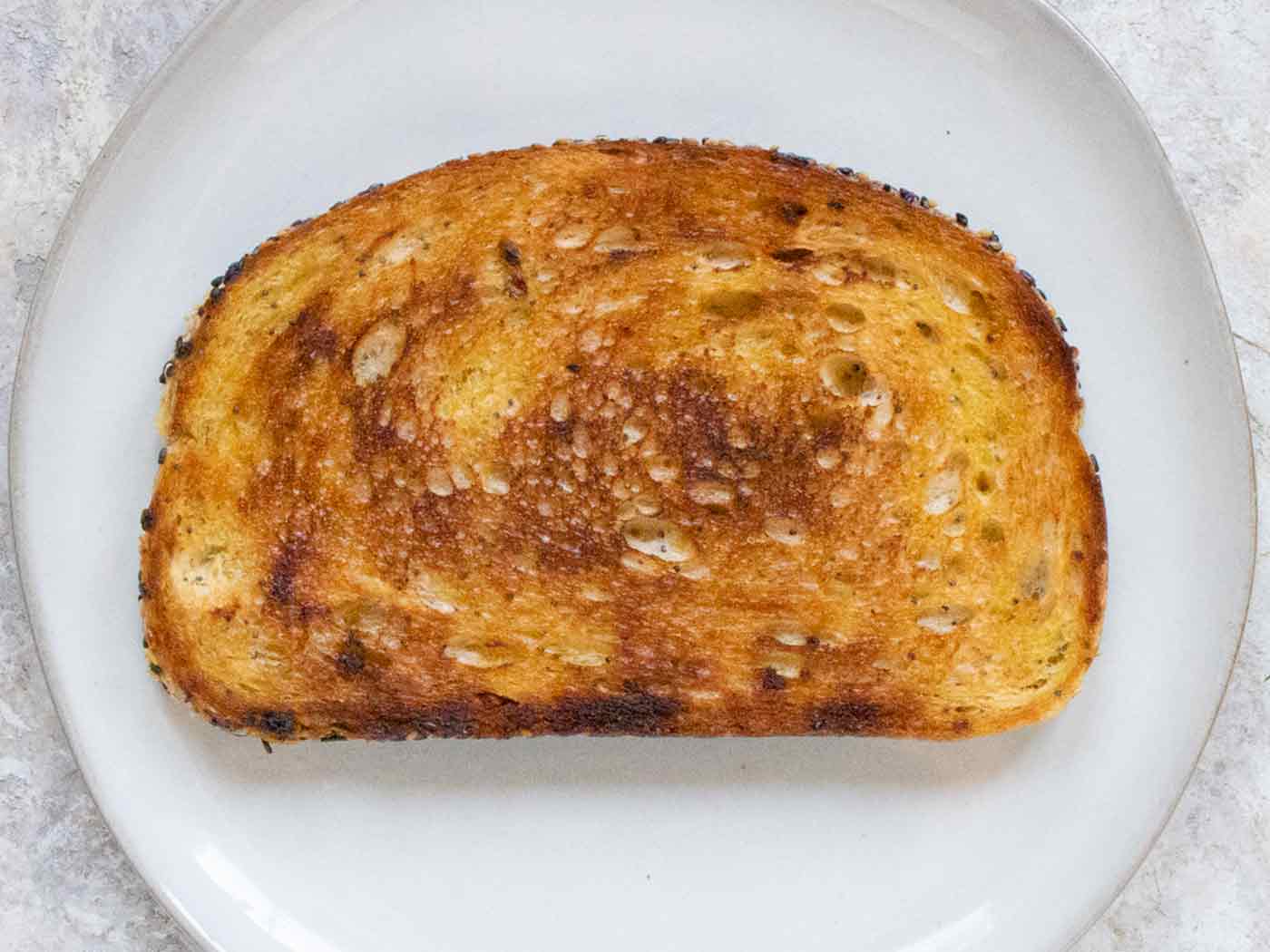 Overhead view of a slice of golden brown fried toast, ready for toppings, on a gray plate.