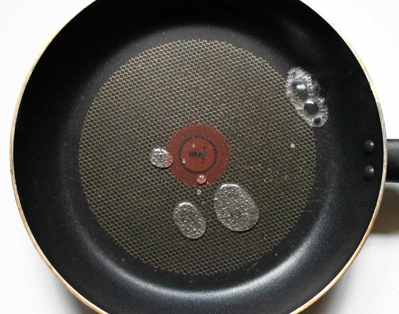 Drops of water sizzling on the surface of a hot skillet.