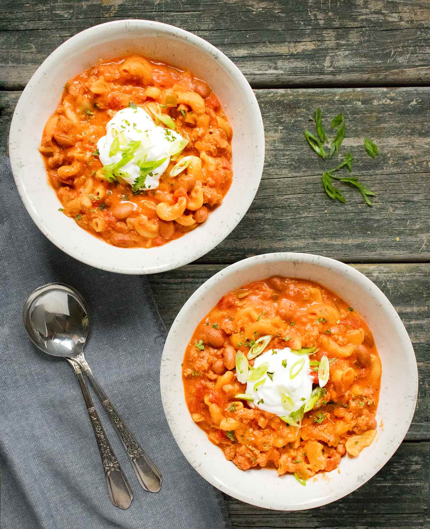 Two bowls of Instant Pot Chili Mac with Turkey, topped with sour cream and green onions
